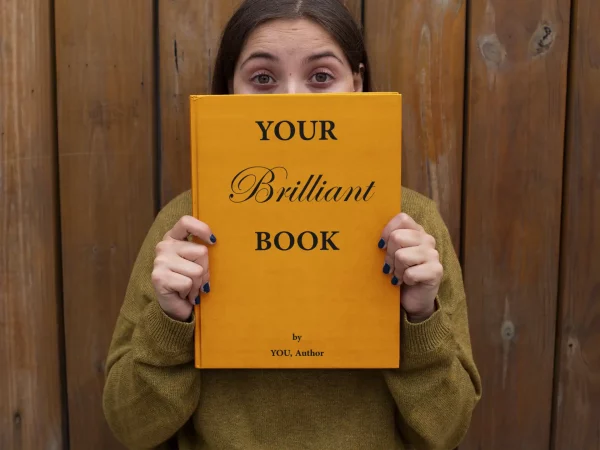 woman-holding-a-book-cover-mockup-with-her-eyes-wide-open